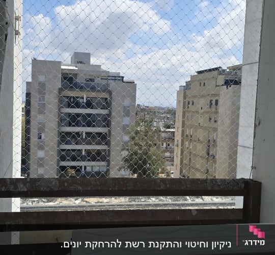 רשת יונים מותקנת על מרפסת עם נוף לבניינים